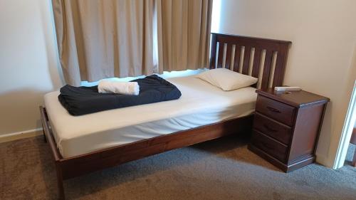 a small bed with a wooden frame and a night stand at Homestay Family room, near the city center in Christchurch