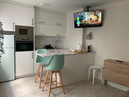 奧維多的住宿－Gascona 26 - Pleno centro, Muy tranquilo, Parking gratis en mismo edificio, Ascensor, Wifi，厨房配有带椅子的柜台,墙上设有电视。