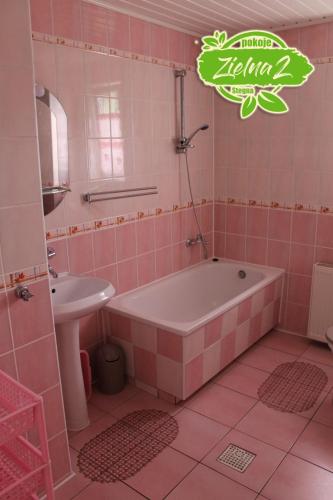 a pink bathroom with a tub and a sink at Apartament Zielna 2 in Stegna