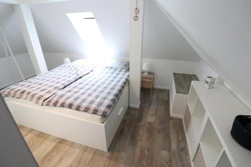 Habitación blanca pequeña con cama y espejo en Appartementhaus-Kogge-Wohnung-12, en Cuxhaven
