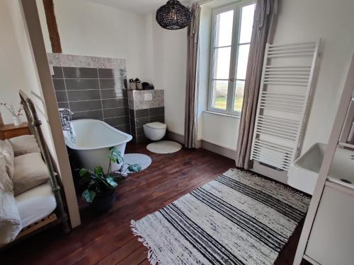 a bathroom with a tub and a sink and a window at Le Brasseur Logements in Saint-Caprais