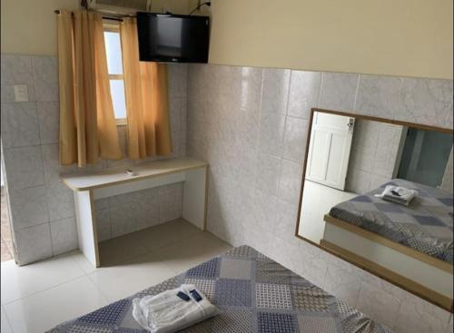 um pequeno quarto com uma cama e um espelho em Hotel Central em Niterói