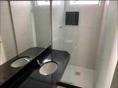 uma casa de banho com 2 lavatórios e uma cabina de duche em vidro. em Hotel Central em Niterói
