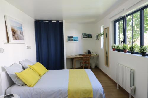 a bedroom with a bed with yellow pillows and a desk at Le cabanon in La Rochelle
