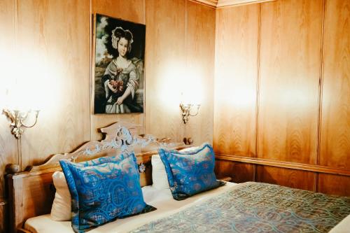 a bedroom with a bed with blue pillows and a painting at Atlas Grand Hotel in Garmisch-Partenkirchen