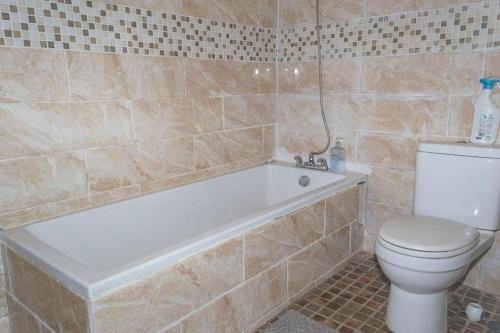 a bathroom with a toilet and a bath tub at M & B Residence in Freetown