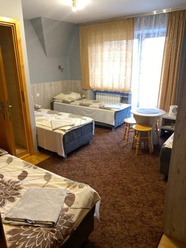 Habitación con 3 camas, mesa y ventana en Domek Okno na Tatry - Dom na wyłączność, en Poronin