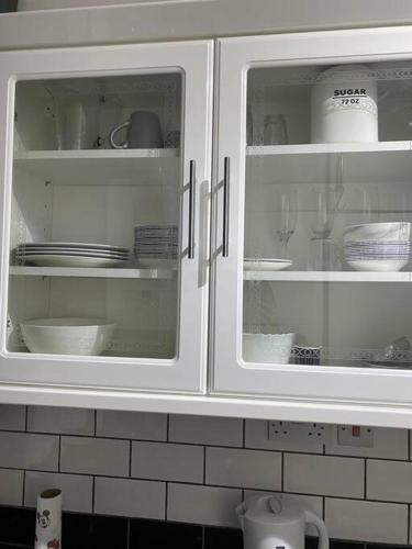 a white kitchen cabinet with dishes in it at Ground Floor One Bedroom Bayswater Central London in London
