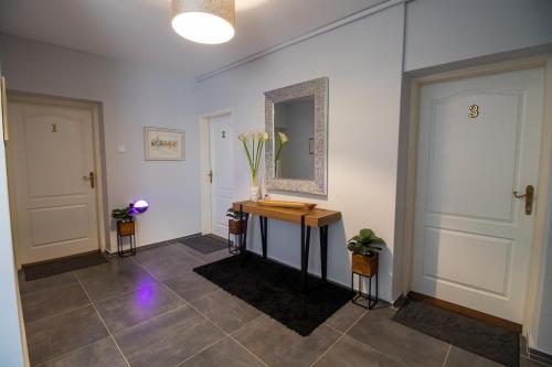 a hallway with a table and a mirror on the wall at Rooms BAUMAN in Osijek