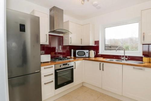 a kitchen with white cabinets and a stainless steel refrigerator at Sealladh in Port Appin