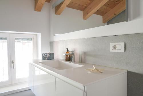 a white kitchen with a sink and a window at Casa Riccardo in Levico Terme