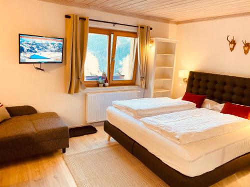 a bedroom with a bed and a couch and a television at ALM SEASONS Premium Chalet & Studios in Saalbach-Hinterglemm