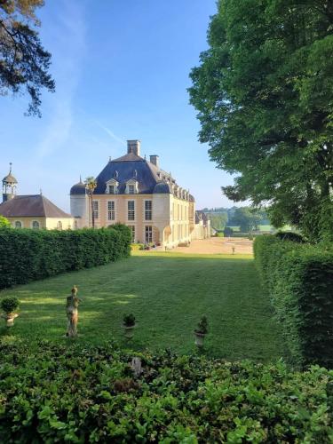 Un homme debout dans l'herbe devant une grande maison dans l'établissement Château du Boschet chambre de l’infatigable gentilhomme, à Bourg-des-Comptes