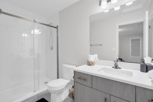 a white bathroom with a toilet and a sink at Lavish Home on Scenic Mountain - King Bed in Hamilton