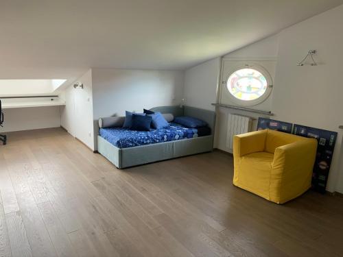 1 dormitorio con 1 cama y 1 silla amarilla en Arianna Golf - Appartamento con camino e sauna golf club Margara en Fubine