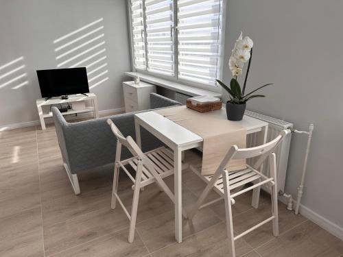 une salle à manger avec une table, des chaises et une télévision dans l'établissement APARTAMENT OŚ. ZŁOTE 5F, à Dzierżoniów