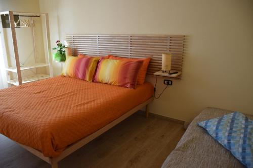 een slaapkamer met een bed met oranje lakens en kussens bij La Lanterna di Franca e Cassio in Pisa