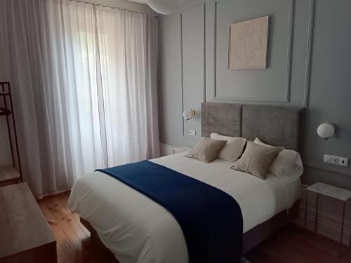 a bedroom with a large bed with white and blue sheets at Quinta dos Tojais Hotel Rural in Celorico de Basto