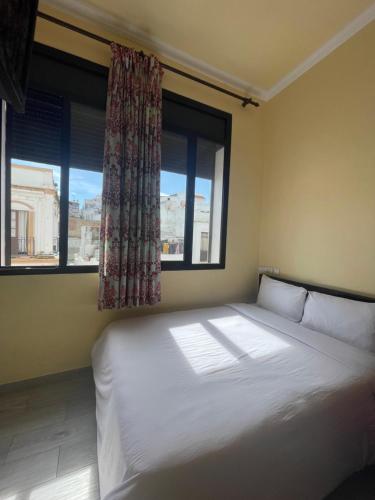 a bed in a room with two windows at Hotel Mauritania in Tangier