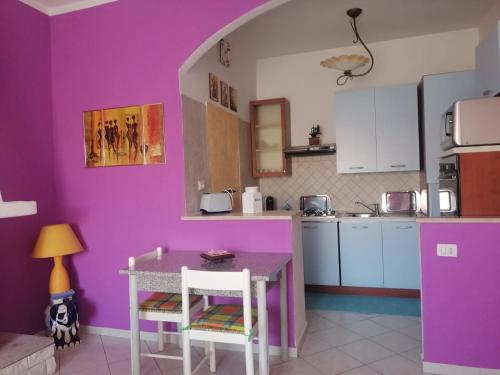 uma cozinha com paredes roxas e uma mesa e cadeiras em Monolocale em Calangianus