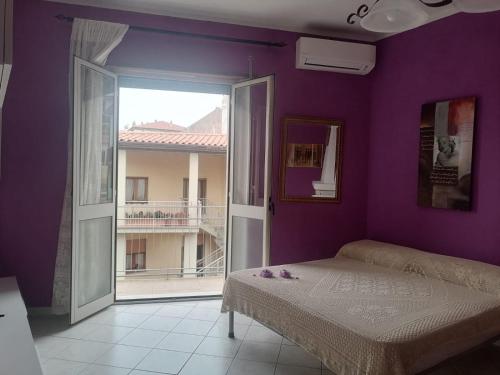 una camera da letto con pareti viola, un letto e una finestra di Monolocale a Calangianus