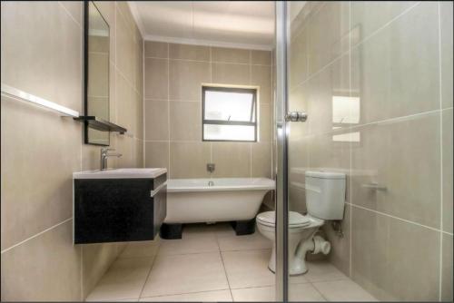 een badkamer met een bad, een toilet en een wastafel bij Revina’s Greenstone 3Bed Luxury Holiday Apartment in Johannesburg