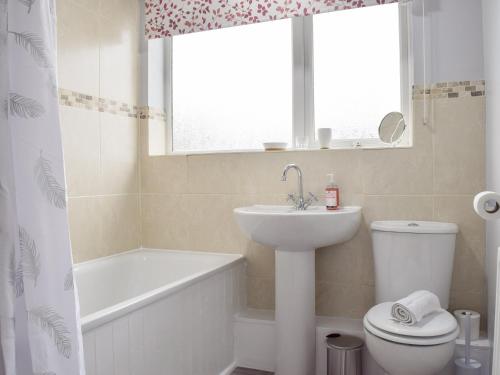 uma casa de banho com um lavatório, um WC e uma janela. em Baileys Tavern em Wartnaby