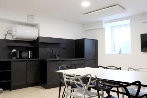 Lumi - modern apartment with parking في ماريبور: مطبخ مع دواليب سوداء وطاولة وكراسي بيضاء