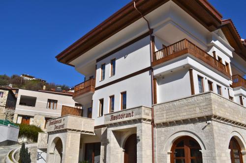 um edifício branco com uma varanda em cima em Hotel Rezidenca Desaret em Berati