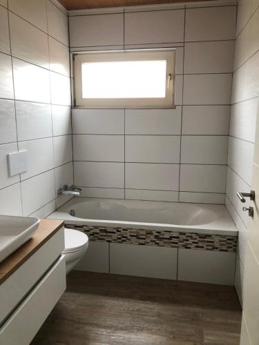 a bathroom with a tub and a toilet and a window at Brockenblick in Braunlage