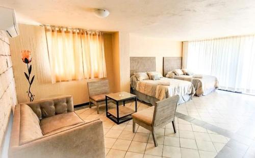 um quarto de hotel com duas camas e um sofá em HOTEL MARIA ISABEL DE IGUALA em Iguala de la Independencia