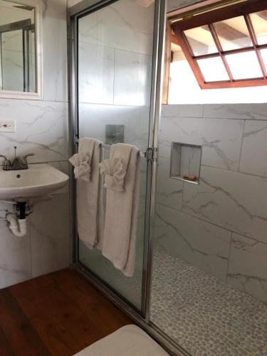 a bathroom with a shower and a sink with towels at Tree House Luxe in Saint Annʼs Bay