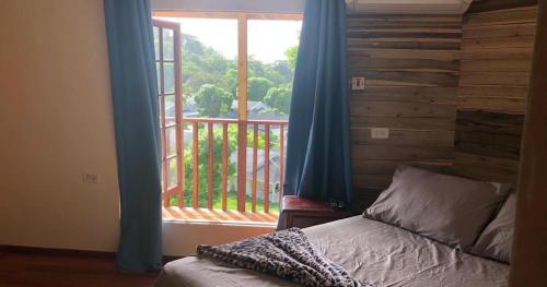 a bedroom with a bed and a window with a balcony at Tree House Luxe in Saint Annʼs Bay