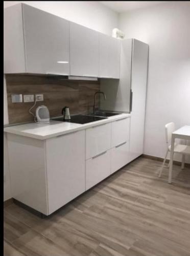 uma cozinha com armários brancos, um lavatório e uma mesa em Appartamento il Torchio em Lecco