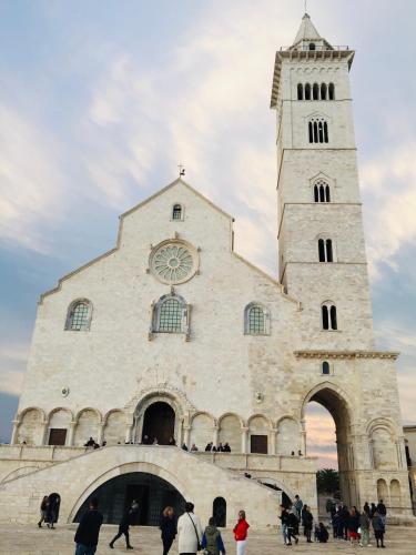 a large building with a clock tower with people walking around it at Loft Carrettieri Affittacamere by Le Marinelle in Trani