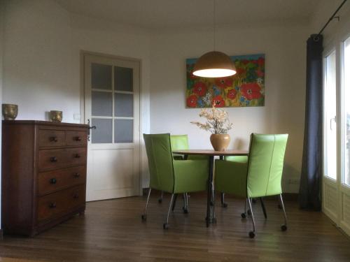 une salle à manger avec une table et des chaises vertes dans l'établissement Domaine la Borniotte, à Saint-Alvère