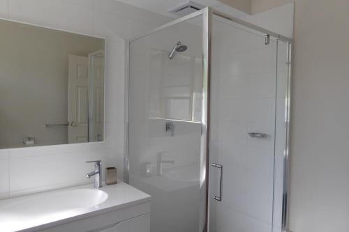 a white bathroom with a shower and a sink at Sea Banksia in Denmark