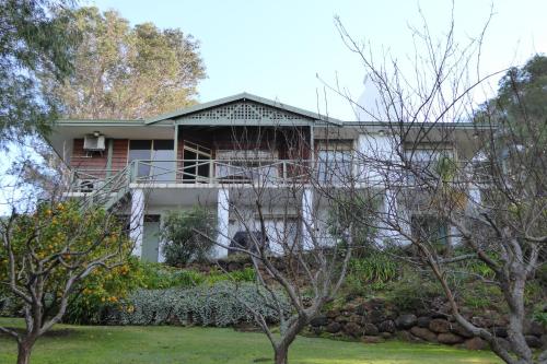 a house with a balcony and trees in front of it at Sea Banksia in Denmark