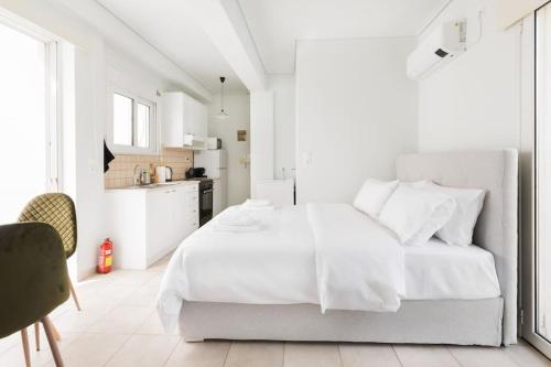 a white bedroom with a white bed and a kitchen at Adorable sunny studio with private balcony I in Athens
