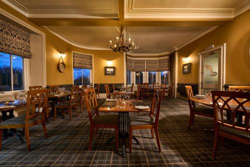 un restaurante con mesas y sillas de madera y una lámpara de araña en Ulbster Arms Hotel near Thurso, en Halkirk