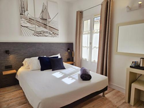 um quarto com uma grande cama branca num quarto em Hôtel du Port em Saint-Martin-de-Ré