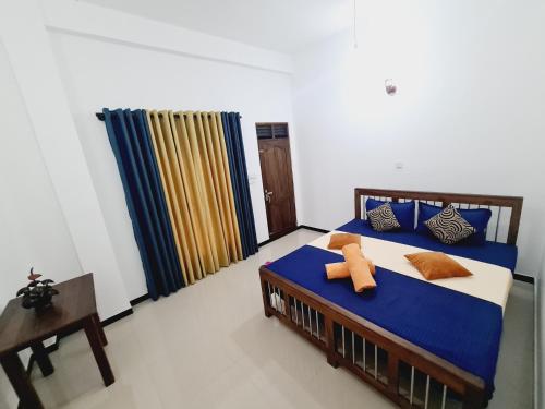 a bedroom with a bed with blue sheets and a window at Jungle Lodge in Udawalawe
