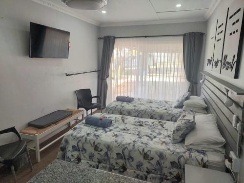 1 dormitorio con 2 camas, escritorio y TV en Rest4Sure, en Ashton