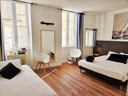 a bedroom with two beds and two chairs and a mirror at Hôtel du Port in Saint-Martin-de-Ré