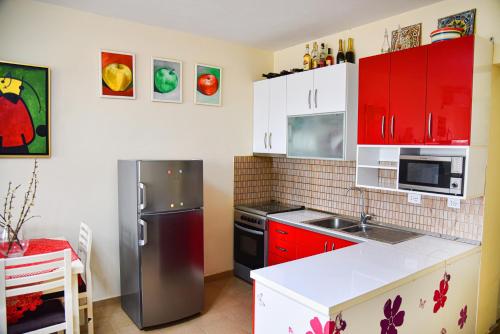 a kitchen with red cabinets and a stainless steel refrigerator at White Sea View Apartment Velipoje in Velipojë