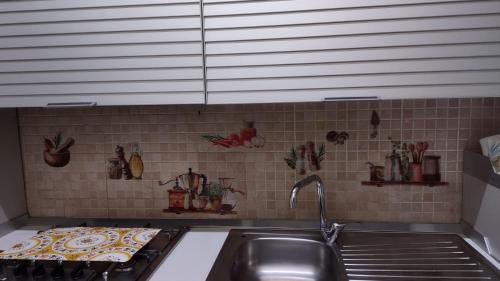 a kitchen with a sink and a tile wall at Casa Primavera in Palermo
