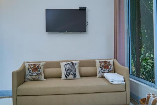 a living room with a couch with pillows and a television at El Bosque Hotel Boutique in Doradal
