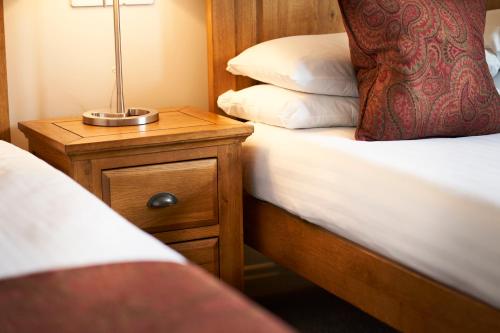 a bedroom with two beds and a night stand with a lamp at Ulbster Arms Hotel near Thurso in Halkirk