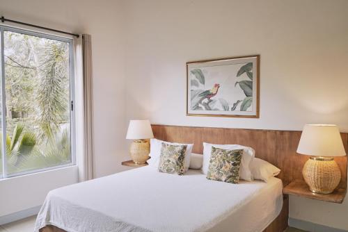 a bedroom with a bed with two lamps and a window at El Bosque Hotel Boutique in Doradal