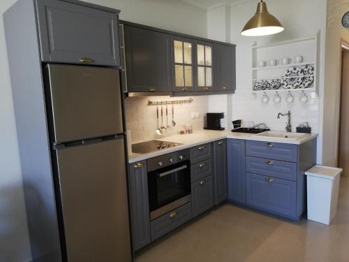 a kitchen with blue cabinets and a black refrigerator at Goldfish Seaside Luxury Houses in Kómi